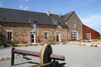 Lit double avec une parure à motifs végétaux verts et blancs, encadré par deux tables de chevet avec lampes allumées.