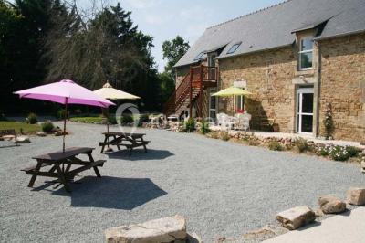 Lit double avec une parure à motifs végétaux verts et blancs, encadré par deux tables de chevet avec lampes allumées.