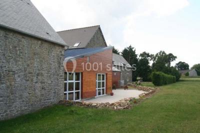 Lit double avec une parure à motifs végétaux verts et blancs, encadré par deux tables de chevet avec lampes allumées.