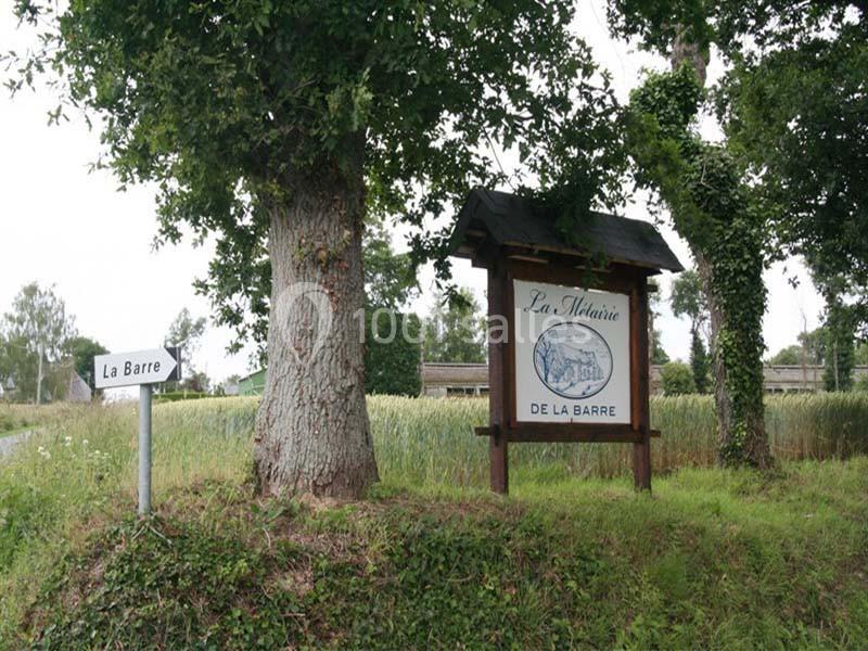 Panneau en bois indiquant ’La Métairie de la Barre’ près d'un arbre, avec un autre panneau ’La Barre’ à gauche.