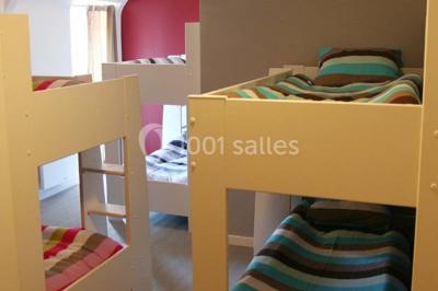 Lit double avec une parure à motifs végétaux verts et blancs, encadré par deux tables de chevet avec lampes allumées.