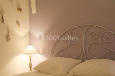 Lit double avec une parure à motifs végétaux verts et blancs, encadré par deux tables de chevet avec lampes allumées.