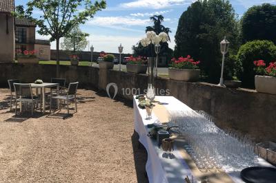 Allée bordée d'arbres et d'arbustes, avec un sol en gravier sous un ciel bleu dégagé.
