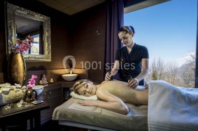 Deux personnes jouent au mini-golf sur un terrain entouré de végétation, avec une cabane perchée visible en arrière-plan.