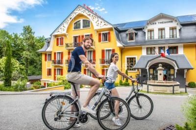 Deux personnes jouent au mini-golf sur un terrain entouré de végétation, avec une cabane perchée visible en arrière-plan.