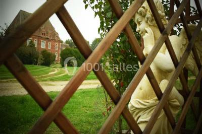 Cheminée ancienne en pierre avec un bas-relief sculpté, encadrée par un mur bleu et un plafond en bois.