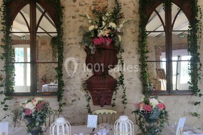 Cheminée ancienne en pierre avec un bas-relief sculpté, encadrée par un mur bleu et un plafond en bois.