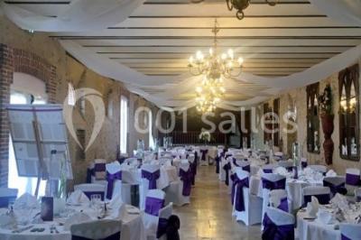 Cheminée ancienne en pierre avec un bas-relief sculpté, encadrée par un mur bleu et un plafond en bois.