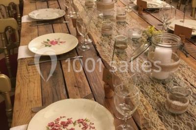 Cheminée ancienne en pierre avec un bas-relief sculpté, encadrée par un mur bleu et un plafond en bois.