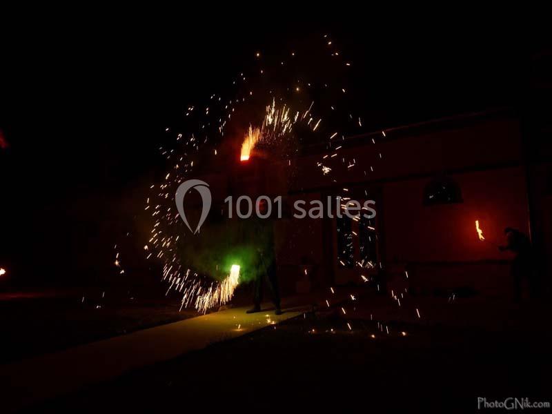 Personne jonglant avec des objets enflammés, créant des étincelles lumineuses dans un environnement nocturne.