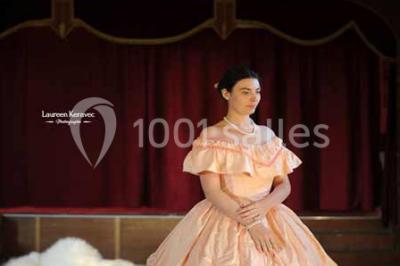 Cheminée ancienne en pierre avec un bas-relief sculpté, encadrée par un mur bleu et un plafond en bois.