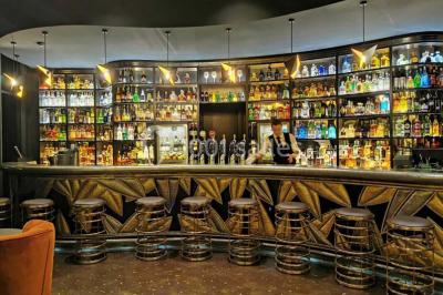 Salle de bain moderne avec lavabo blanc, douche vitrée, murs carrelés sombres et éclairage chaleureux.