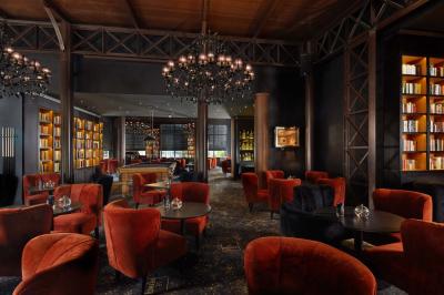 Salle de bain moderne avec lavabo blanc, douche vitrée, murs carrelés sombres et éclairage chaleureux.