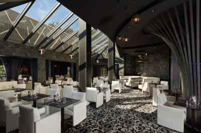 Salle de bain moderne avec lavabo blanc, douche vitrée, murs carrelés sombres et éclairage chaleureux.