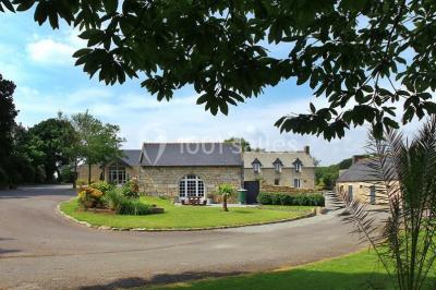 Chambre lumineuse avec un lit double couvert d'une housse à motifs noirs et blancs, près d'une fenêtre avec rideaux clairs.