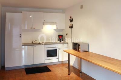 Chambre lumineuse avec un lit double couvert d'une housse à motifs noirs et blancs, près d'une fenêtre avec rideaux clairs.