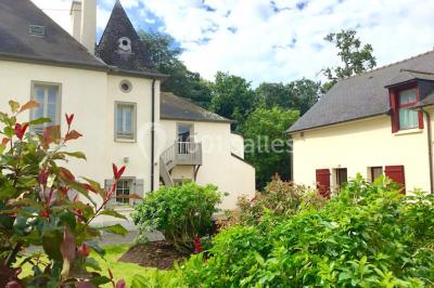 Vue d'un jardin avec pelouse, arbres, bancs rouges et une statue au centre, sous un ciel dégagé.