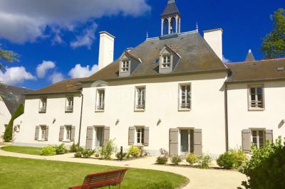 Vue d'un jardin avec pelouse, arbres, bancs rouges et une statue au centre, sous un ciel dégagé.