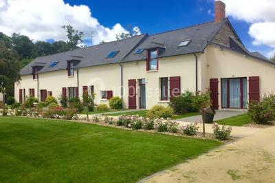 Vue d'un jardin avec pelouse, arbres, bancs rouges et une statue au centre, sous un ciel dégagé.