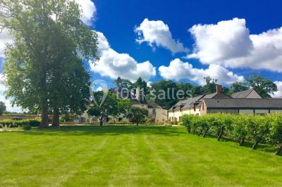 Vue d'un jardin avec pelouse, arbres, bancs rouges et une statue au centre, sous un ciel dégagé.