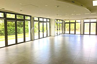 Vue d'un jardin avec pelouse, arbres, bancs rouges et une statue au centre, sous un ciel dégagé.