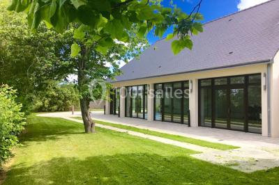 Vue d'un jardin avec pelouse, arbres, bancs rouges et une statue au centre, sous un ciel dégagé.