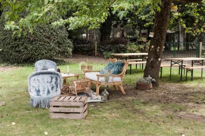 Vue d'un jardin avec pelouse, arbres, bancs rouges et une statue au centre, sous un ciel dégagé.