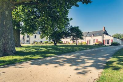 Vue d'un jardin avec pelouse, arbres, bancs rouges et une statue au centre, sous un ciel dégagé.