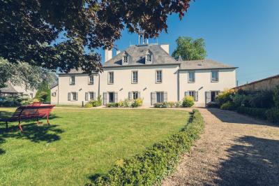 Vue d'un jardin avec pelouse, arbres, bancs rouges et une statue au centre, sous un ciel dégagé.