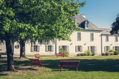 Vue d'un jardin avec pelouse, arbres, bancs rouges et une statue au centre, sous un ciel dégagé.
