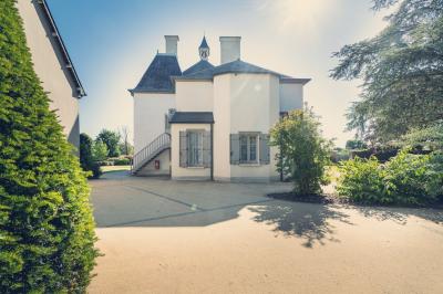 Vue d'un jardin avec pelouse, arbres, bancs rouges et une statue au centre, sous un ciel dégagé.