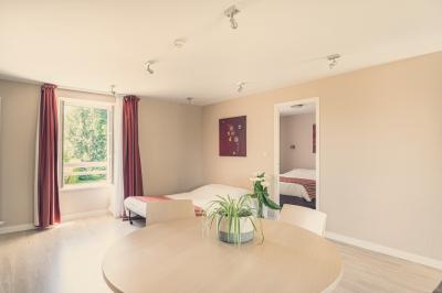 Vue d'un jardin avec pelouse, arbres, bancs rouges et une statue au centre, sous un ciel dégagé.