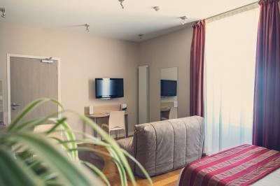 Vue d'un jardin avec pelouse, arbres, bancs rouges et une statue au centre, sous un ciel dégagé.