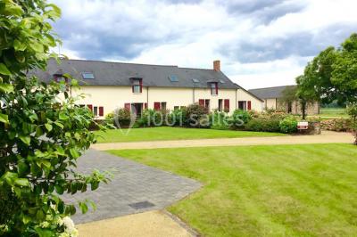 Chambre lumineuse avec lit, canapé, télévision murale, bureau et grande fenêtre avec rideaux rouges.