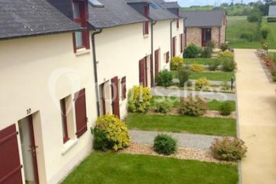 Chambre lumineuse avec lit, canapé, télévision murale, bureau et grande fenêtre avec rideaux rouges.