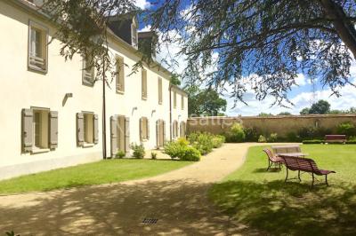 Chambre lumineuse avec lit, canapé, télévision murale, bureau et grande fenêtre avec rideaux rouges.