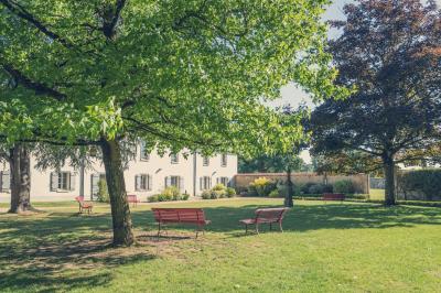Chambre lumineuse avec lit, canapé, télévision murale, bureau et grande fenêtre avec rideaux rouges.