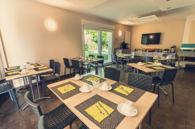 Chambre lumineuse avec lit, canapé, télévision murale, bureau et grande fenêtre avec rideaux rouges.
