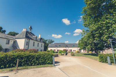 Chambre lumineuse avec lit, canapé, télévision murale, bureau et grande fenêtre avec rideaux rouges.