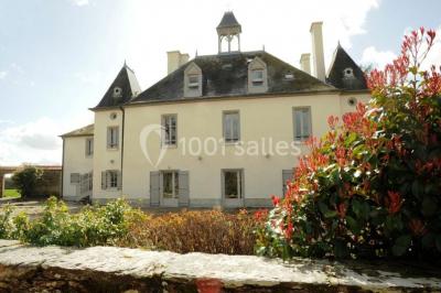 Chambre lumineuse avec lit, canapé, télévision murale, bureau et grande fenêtre avec rideaux rouges.
