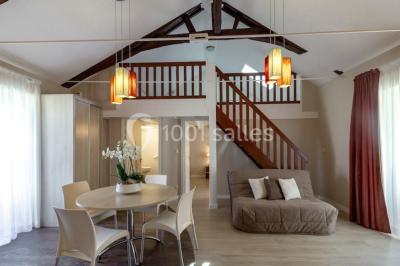 Miniature Chambre Salle à manger lumineuse avec table ronde, chaises blanches, canapé beige, poutres apparentes et escalier en bois.