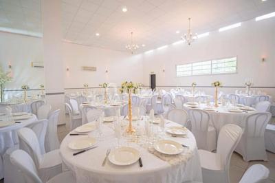Table de réception élégamment dressée avec nappes blanches, serviettes décorées, verres et couverts alignés.