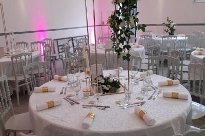 Table de réception élégamment dressée avec nappes blanches, serviettes décorées, verres et couverts alignés.
