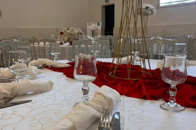 Table de réception élégamment dressée avec nappes blanches, serviettes décorées, verres et couverts alignés.