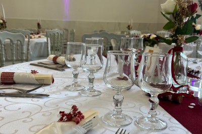 Table de réception élégamment dressée avec nappes blanches, serviettes décorées, verres et couverts alignés.
