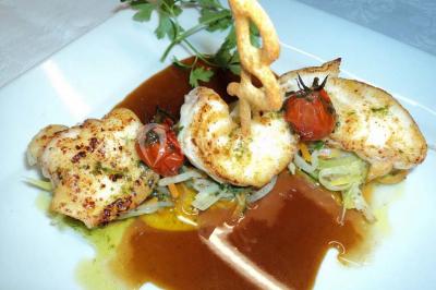 Grande pelouse bordée d'arbres avec une structure couverte et des chaises disposées en extérieur.