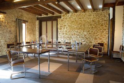 Grande pelouse bordée d'arbres avec une structure couverte et des chaises disposées en extérieur.