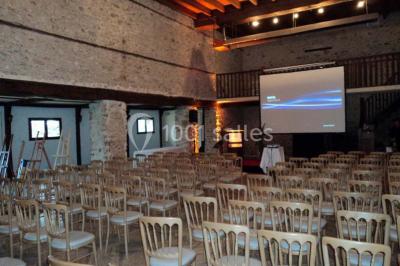 Grande pelouse bordée d'arbres avec une structure couverte et des chaises disposées en extérieur.