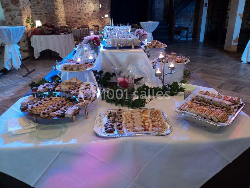 Buffet de réception avec une variété de plats et desserts disposés sur des tables décorées de bougies et de feuillage.