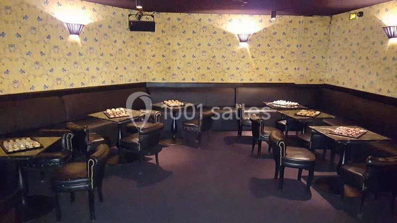 Salle avec des tables basses noires, chaises en cuir et murs décorés de papier peint à motifs jaunes et bleus.